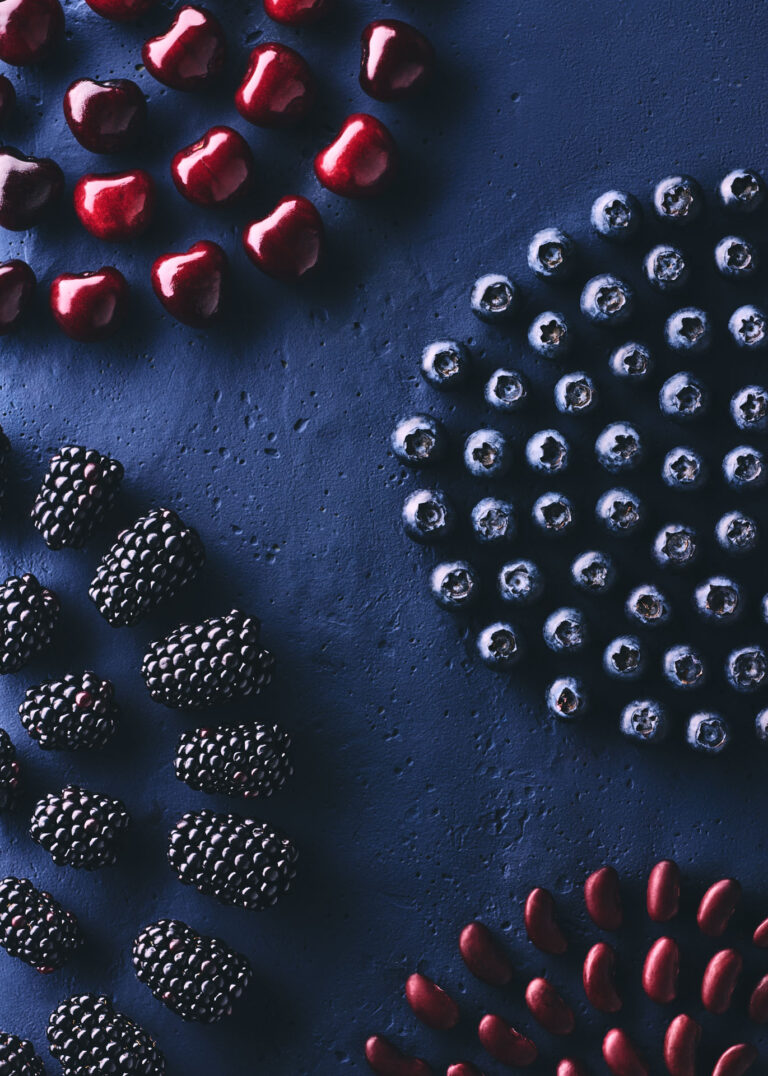 Conceptual and editorial food photography for a design calendar, combining artistic culinary arrangements with structured geometric forms, concluding the first set with a rich dark blue composition of arranged blueberries, blackberries, and glossy cherries.