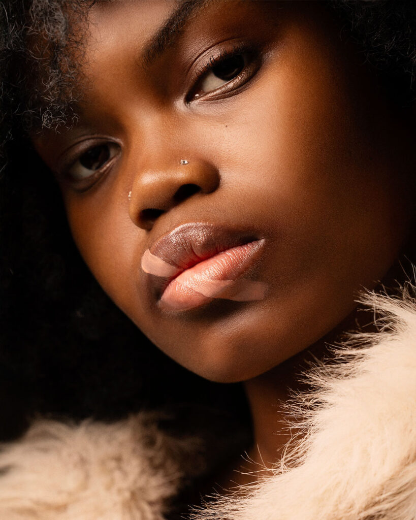 Professional beauty campaign image for Faber-Castell Cosmetics featuring clean studio portraits with diverse models and soft lighting that defines natural contours and warm earth tones, showcasing a dramatic beauty close-up emphasizing deep shadows and sophisticated lip textures.