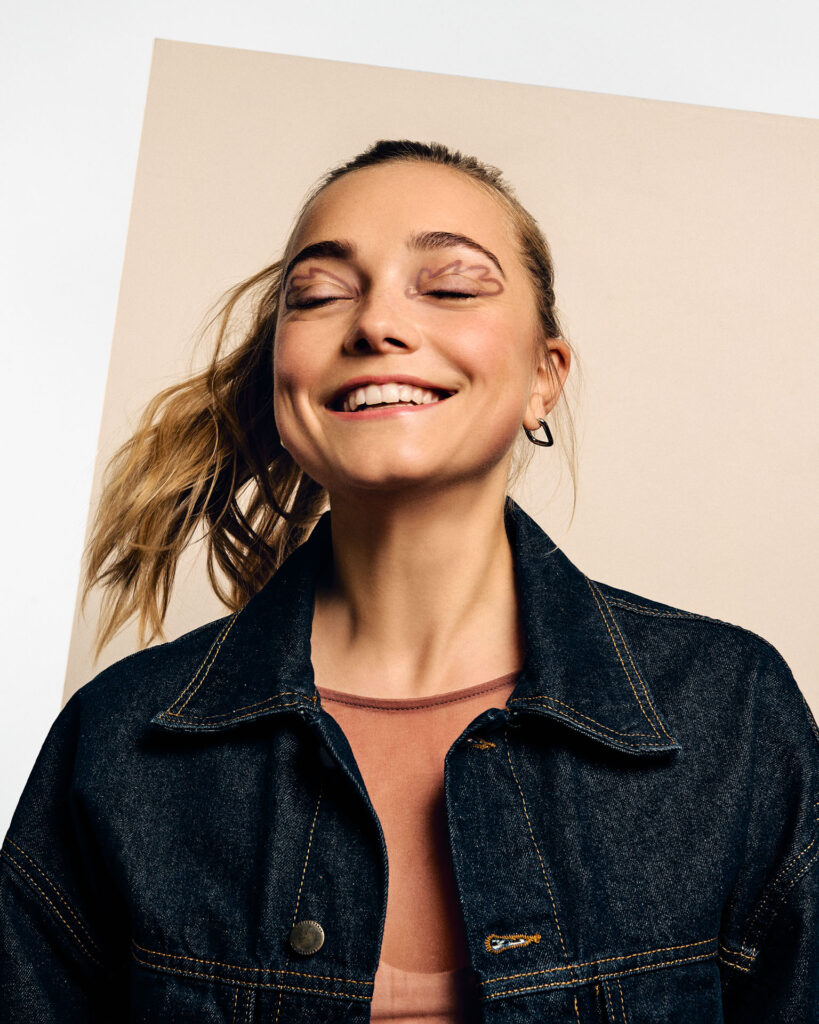 High-fashion beauty commercial shot for Faber-Castell Cosmetics featuring multiple models, capturing the sharp metallic reflection and radiance of glitter pigments on the skin under direct lighting, highlighting a natural, expressive studio moment with subtle glitter textures on the eyelids.