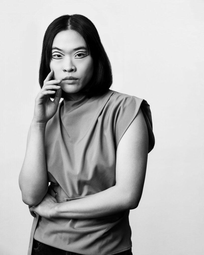 Professional beauty campaign image for Faber-Castell Cosmetics featuring clean studio portraits with diverse models and soft lighting that defines natural contours and warm earth tones, showcasing a minimalist black and white portrait emphasizing a clean, structured top and soft shadows.